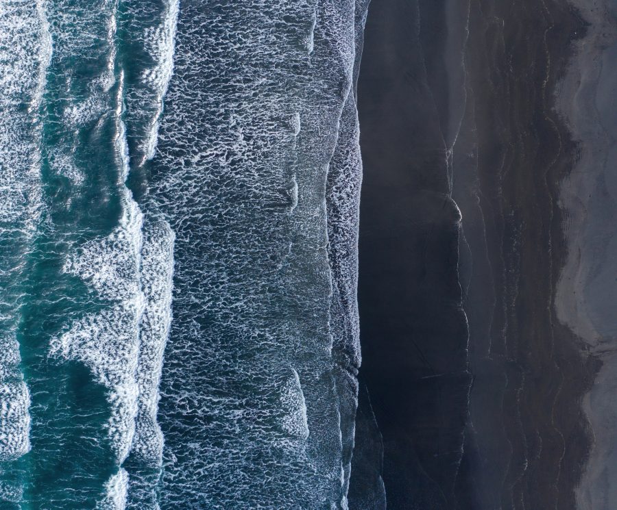 Aerial view of Atlantic ocean waves washing black sandy beach